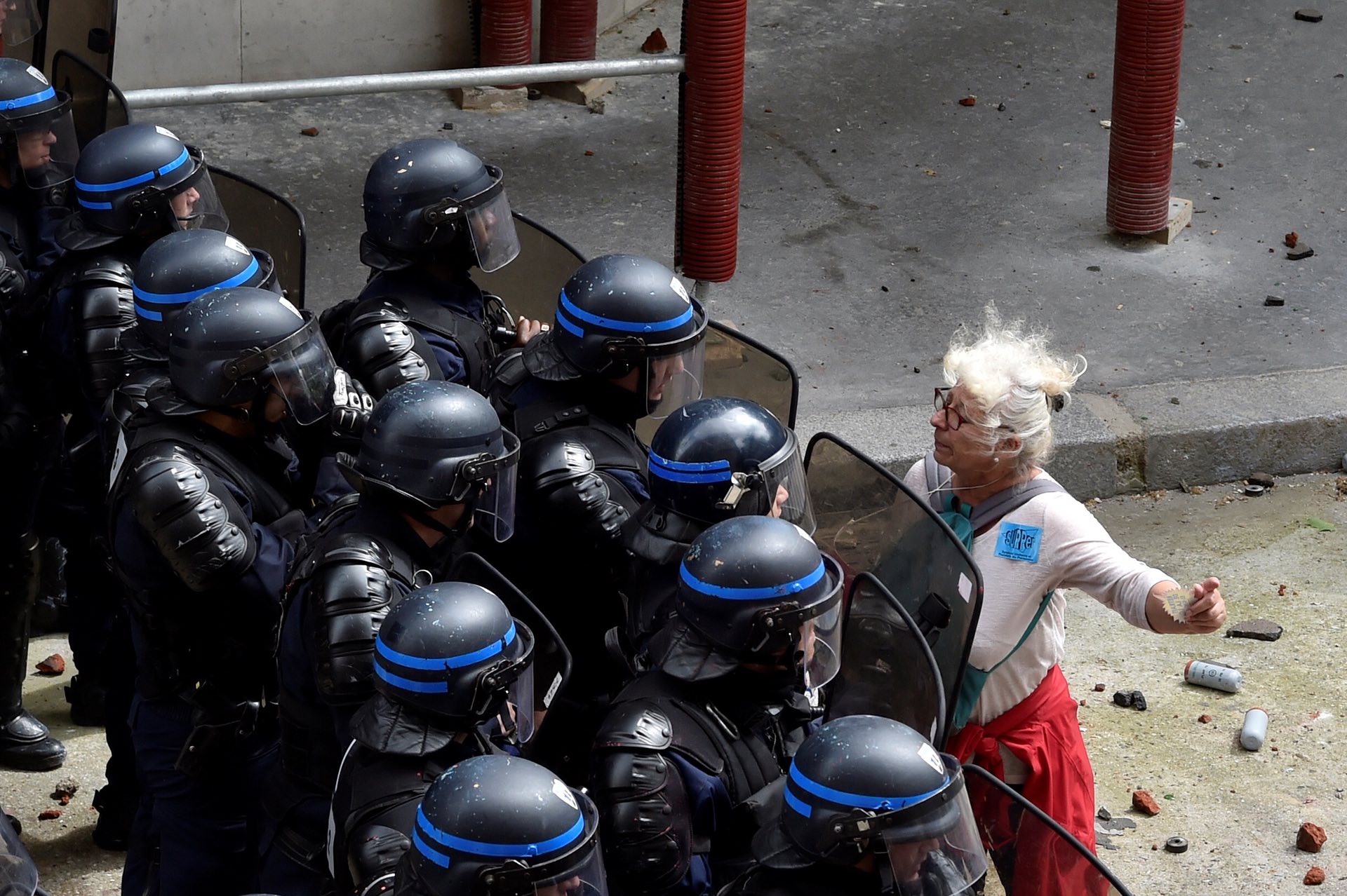 A woman stands in front of police officers as they block access to a street during a protest against proposed labour reforms in Paris on 14 June 2016. PHOTO: AFP