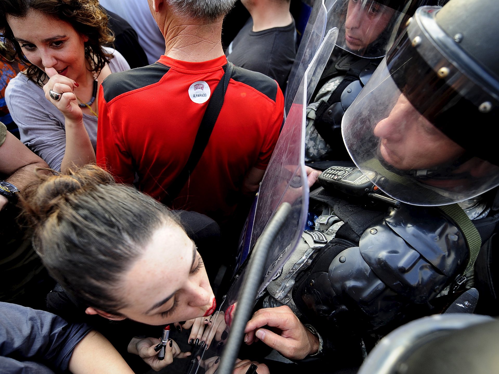 Jasmina Golubovska does her lipstick in the shield of a policeman in front of a government building in Skopje, Macedonia, on 5 May 2015. PHOTO: REUTERS