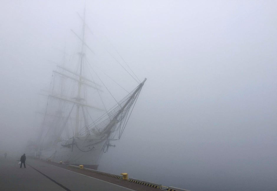A man walks past Dar Pomorza (Gift of Pomerania), a full-rigged sailing ship, now a museum, as thick fog covers the Port of Gdynia, Poland. PHOTO: REUTERS