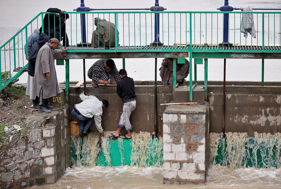 People try to stop water flowing through the gate of a flood channel after incessant rains in Srinagar. PHOTO: REUTERS