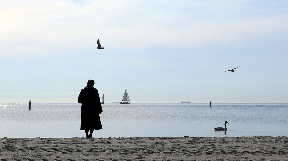 A woman, wrapped adult opposite a cold wind, stands on a beach as she watches a swan and yachts in Gdynia, Poland. PHOTO: REUTERS
