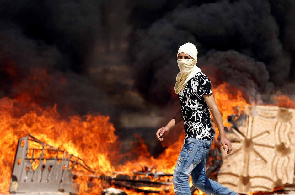 A Palestinian protester walks past a fire during clashes with Israeli troops at a protest in support of Palestinian prisoners on hunger strike in Israeli jails, in the West Bank village of Beita, near Nablus. PHOTO: REUTERS