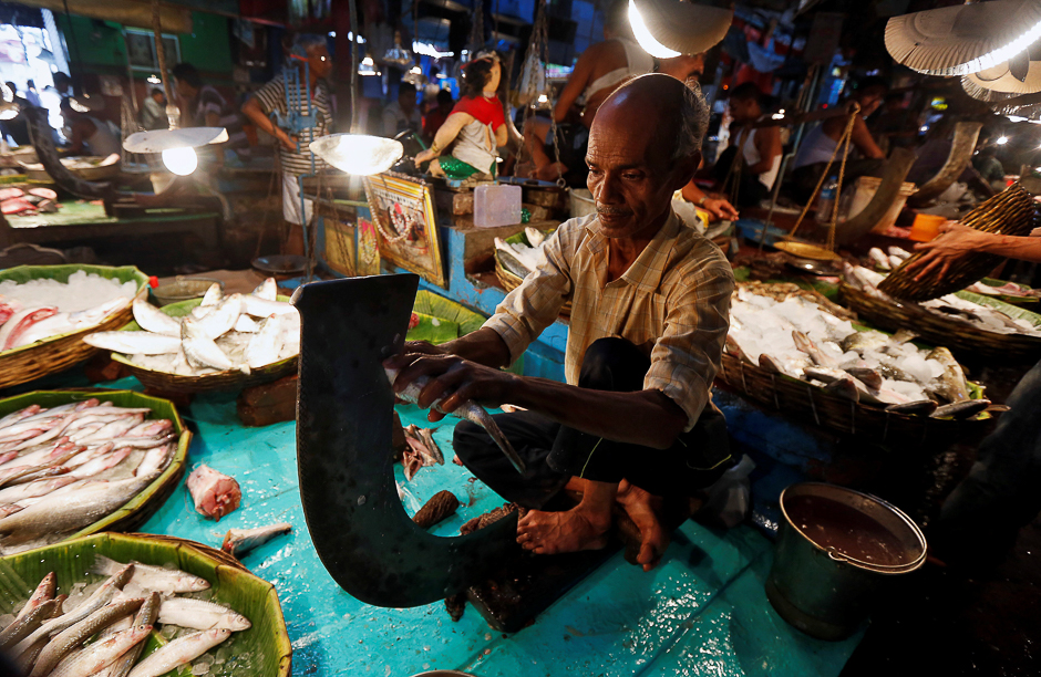 A vendor cuts fish for a customer at a wholesale fish market in Kolkata, India. PHOTO: REUTERS
