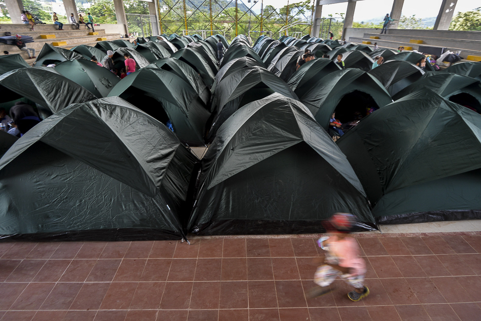 A child runs beside a group of tents at a shelter in Mocoa, Putumayo department, southern Colombia. Residents of Mocoa were Monday desperately searching for loved ones missing since devastating mudslides slammed into the remote Colombian town, as the death toll soared to over 250, including 43 children. PHOTO: AFP