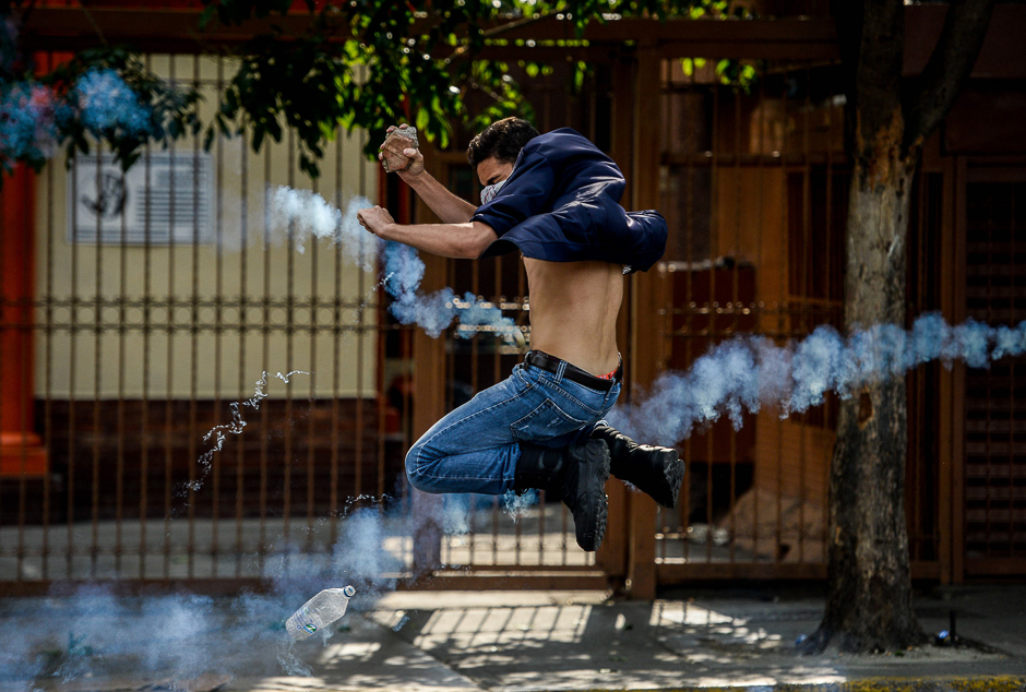 An opposition activist thows a stone at riot police during clashes following a protest against President Nicolas Maduro in Caracas. PHOTO: AFP