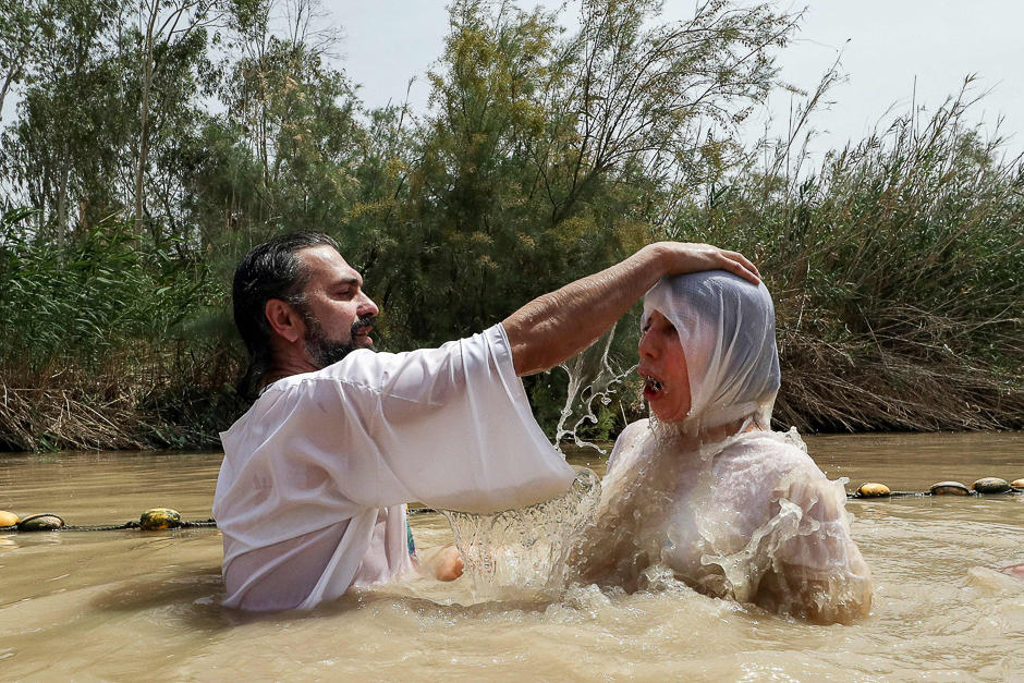 A Christian pilgrim is baptised by a priest in the muddy water of the Jordan River at the Kasser-Al-Yahud baptismal site near the West Bank city of Jericho. PHOTO: AFP