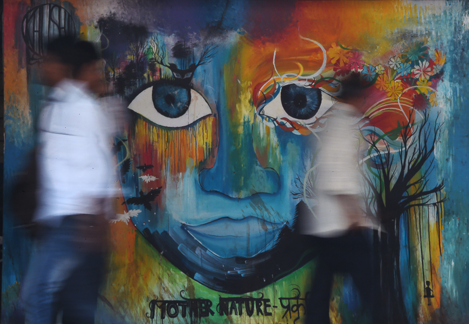 Indian officegoers walk past a wall displaying a mural in Mumbai. Graffiti featuring as social awareness messages, civic causes, religious figures, politicians, as well as daily life scenes cover the walls of certain streets of Mumbai. PHOTO: AFP