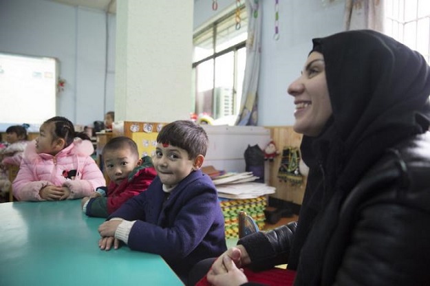 Manar Abdulhussein [L], 38, an Iraqi migrant, laughs in a kindergarten her son Alo-baidi Yousif (M), 4, attends in Yiwu, Zhejiang Province, China 11 January 2017. PHOTO: Thomson Reuters Foundation