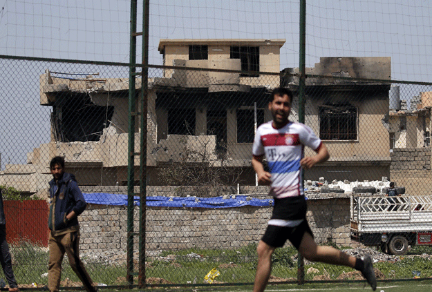 An Iraqi player (R), sporting the jersey of German club Bayern Munich, jogs during a football match in eastern Mosul's al-Salam neighbourhood on April 7, 2017. PHOTO: AFP