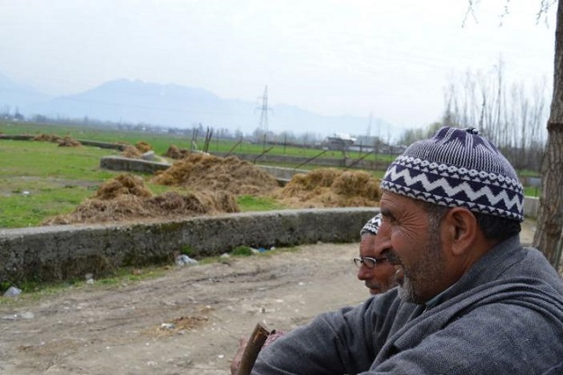 Two elderly Kashmiris chat near agricultural land which is being converted to housing in Pandach-Ganderbal, near Srinagar, March 29, 2017. TRF/Athar Parvaiz