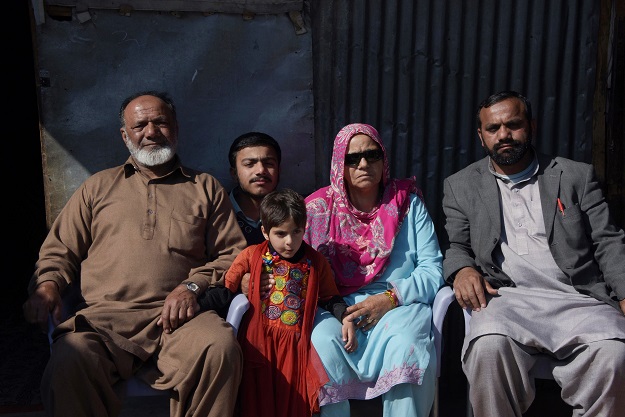 This photograph taken on February 12, 2017, shows elderly Indian Kashmiri Muhammad Ashraf (L) posing for a photograph with his wife Badar Un Nisa (2R) and son Muhammad Asghar (R) upon his arrival at a refugee camp on the outskirts of Muzaffarabad. PHOTO: AFP