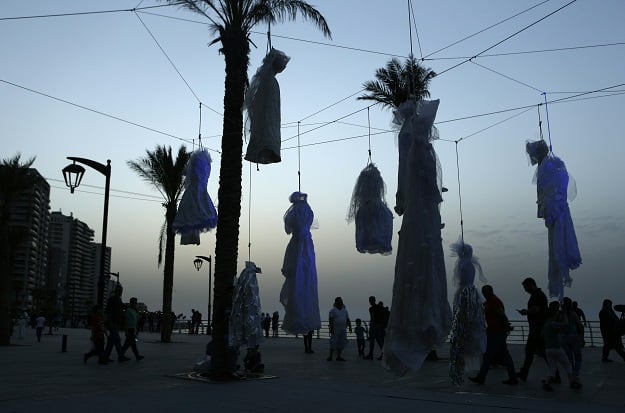 The sun set over an installation of wedding dresses by Lebanese artist Mireille Honein and Abaad NGO at Beirut's Corniche, on April 22, 2017. PHOTO: AFP