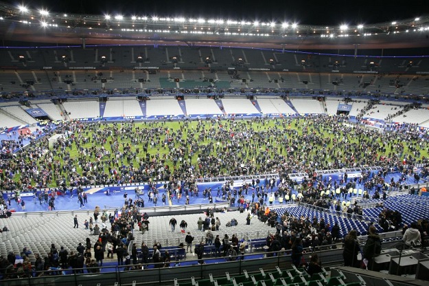 Spectators wait on the pitch of the Stade de France stadium in Seine-Saint-Denis, Paris' suburb on November 13, 2015 after a series of gun attacks occurred across Paris as well as explosions outside the national stadium where France was hosting Germany. At least 18 people were killed, with at least 15 people had been killed at the Bataclan concert hall in central Paris, only around 200 metres from the former offices of Charlie Hebdo which were attacked by jihadists in January. AFP PHOTO / MATTHIEU ALEXANDRE (Photo credit should read MATTHIEU ALEXANDRE/AFP/Getty Images)