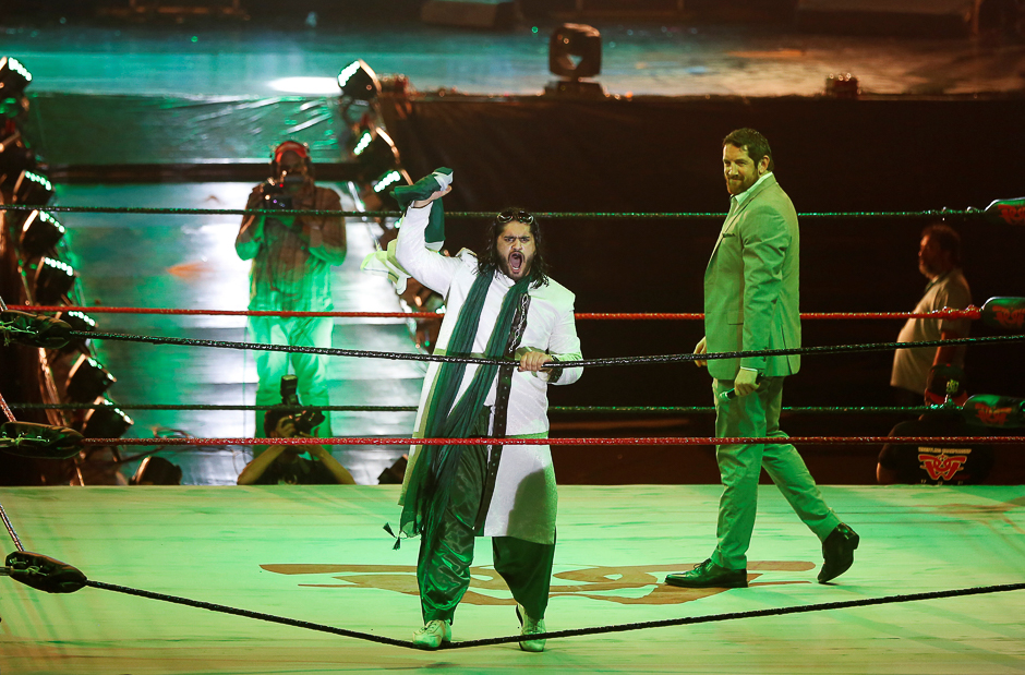 Pakistani wrestler Baadshah Pehalwan Khan holds the national flag as he reacts to the fans during the opening cermoneny of Pro Wresterning Entertainment SHOWI (PWE) in Karachi. PHOTO: REUTERS