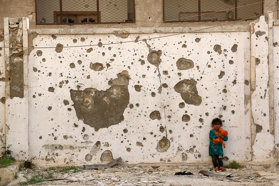 A displaced Syrian girl plays with a cuddly toy in front of a damaged wall in the city of Azaz, situated on the border with Turkey. PHOTO: AFP