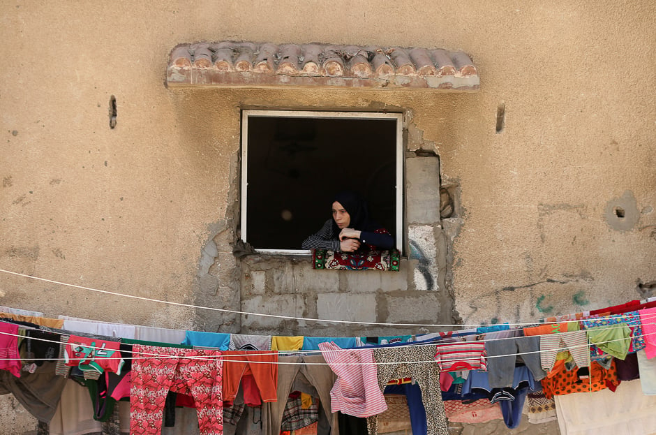 A woman looks out of a house window as she watches the funeral of Palestinian fisherman Mohammed Baker in Gaza City. PHOTO: REUTERS