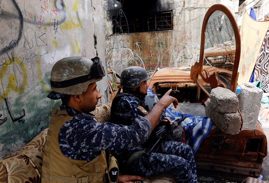 Members of the Iraqi Federal Police look at the positions of Islamic State fighters in a mirror at a frontline in western Mosul. PHOTO: REUTERS