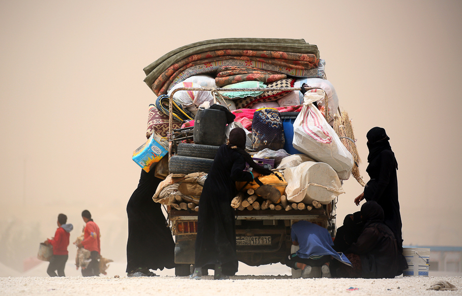 Displaced Syrians who fled the Islamic State (IS) group stronghold of Raqa are seen during a sandstorm at a temporary camp in the northern Syrian village of Ain Issa. PHOTO: AFP