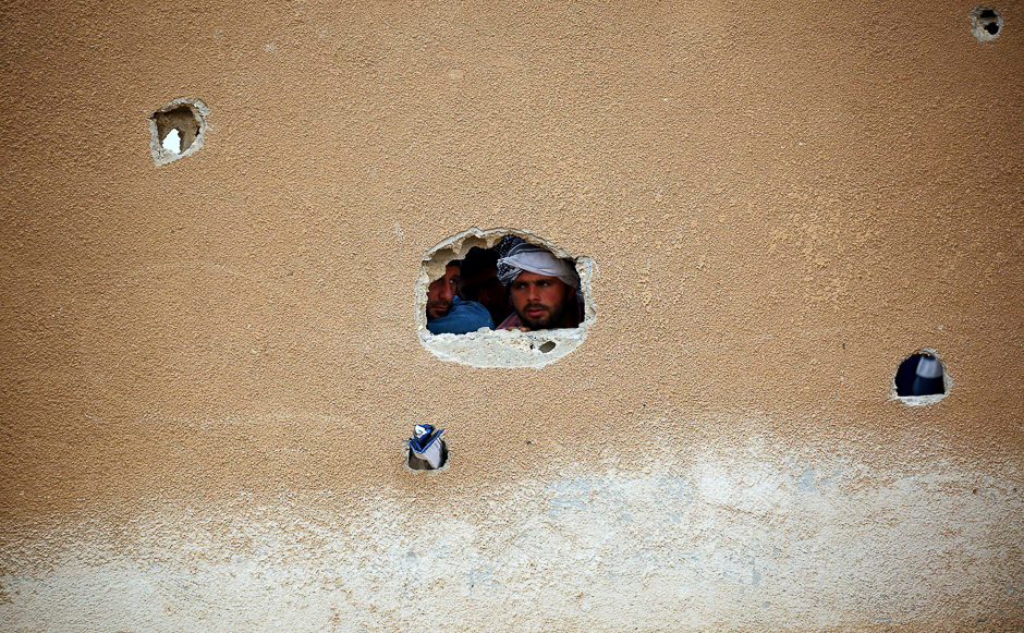 Displaced Syrians, who fled the countryside surrounding the Islamic State (IS) group stronghold of Raqa, look through a hole in a wall at a temporary camp in the village of Ain Issa. PHOTO: AFP