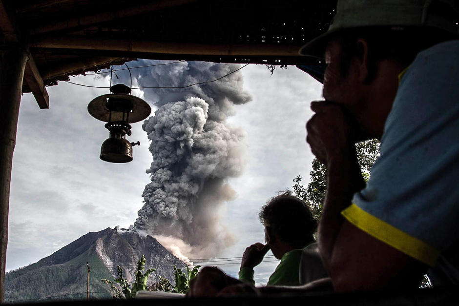 Villagers look on as Mount Sinabung volcano spews thick volcanic ash, as seen from Beganding village in Karo, North Sumatra province. PHOTO: AFP