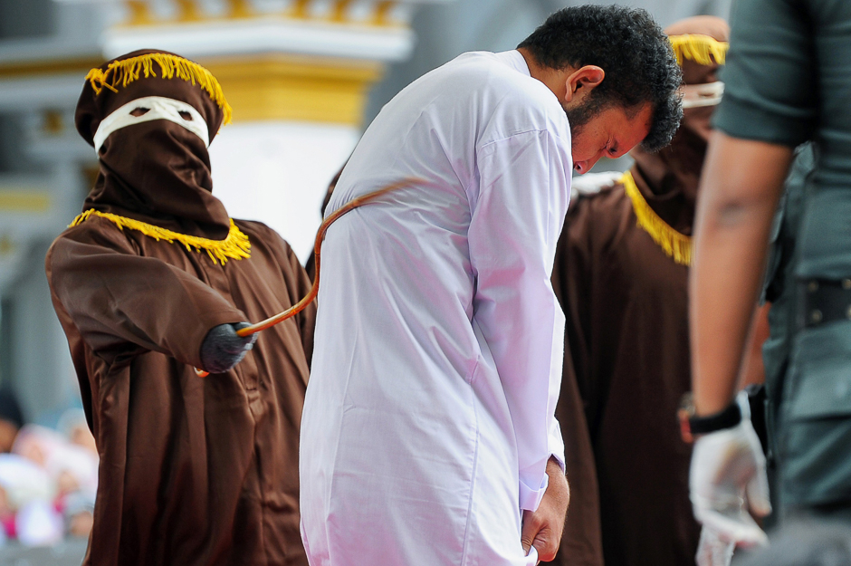 An Indonesian man (C), one of two to be publicly caned for having sex, is caned in Banda Aceh. The pair, aged 20 and 23, were found guilty of having broken sharia rules in conservative Aceh province. PHOTO: AFP
