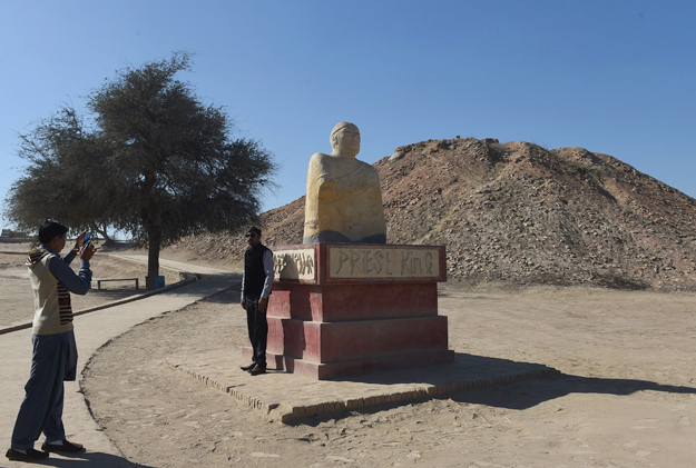 In this photograph taken on February 9, 2017, a visitor takes a photograph beside of replica of a statue of King Priest discovered at the UNESCO World Heritage archeological site of Mohenjo Daro some 425 kms north of the Pakistani city of Karachi. Once the centre of a powerful civilisation, Mohenjo Daro was one of the world's earliest cities -- a Bronze Age metropolis boasting flush toilets and a water and waste system to rival modern standards. Some 5,000 years on archaeologists believe the ruins could unlock the secrets of the Indus Valley people, who flourished around 3,000 BC in what is now India and Pakistan before mysteriously disappearing. PHOTO: AFP