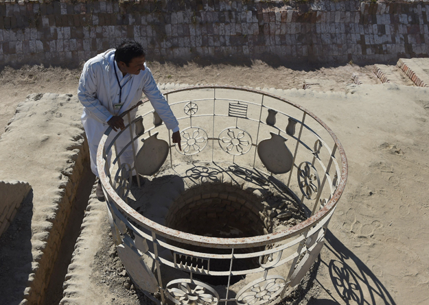 In this photograph taken on February 9, 2017, Pakistani caretaker at the UNESCO World Heritage archeological site of Mohenjo Daro, Ismail Mugheri, points out a well at the site some 425 kms north of Karachi. Once the centre of a powerful civilisation, Mohenjo Daro was one of the world's earliest cities -- a Bronze Age metropolis boasting flush toilets and a water and waste system to rival modern standards. Some 5,000 years on archaeologists believe the ruins could unlock the secrets of the Indus Valley people, who flourished around 3,000 BC in what is now India and Pakistan before mysteriously disappearing. PHOTO: AFP