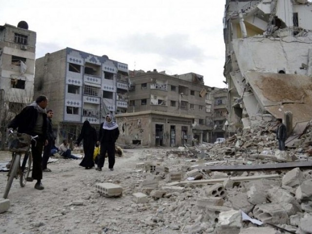 Residents walk past damaged buildings after what activists said were air strikes by forces loyal to Syria's President Bashar al-Assad in the Douma neighborhood of Damascus PHOTO: REUTERS