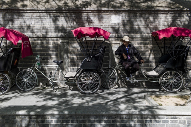 this photo taken on april 24 2017 shows a rickshaw driver waiting for customers in a touristic area in beijing appearing in china at the end of the 19th century rickshaws originally had two wheels and were pulled by their driver on foot with passengers seated at the back today most of the vehicles are tricycles   some still have pedals and are propelled by physical force but the majority are equipped with electric or gas engines photo afp