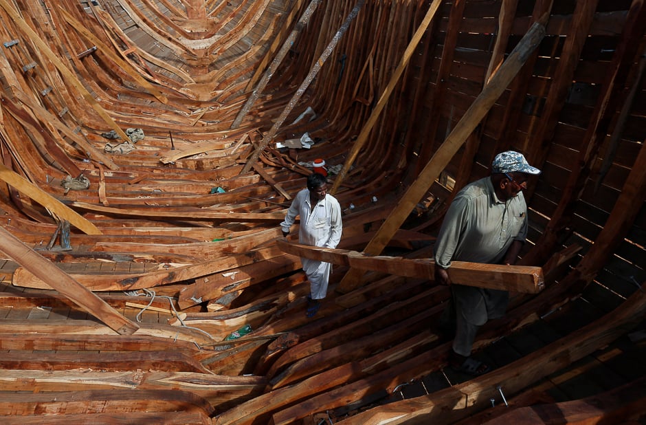 Carpenters carry a wood panel while working to build a boat at a yard in Fish Harbour in Karachi. PHOTO: REUTERS