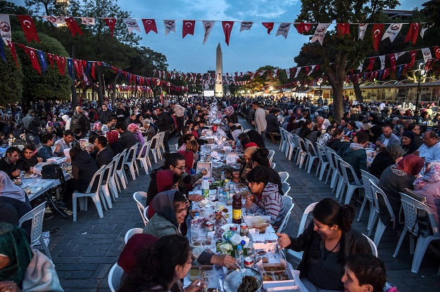 People break their fast on May 27, 2017 at the Blue Mosque Square in Istanbul, during the first day of the holy month of Ramadan. The world's nearly 1.5 billion Muslims on May 27 began Ramadan, the holy month of dawn-to-dusk fasting and prayers. It is sacred to Muslims because tradition says the Koran was revealed to the Prophet Mohammed during that month. / AFP PHOTO / OZAN KOSE