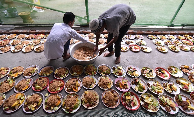 TOPSHOT - Indian Muslim men arrange rows of food for Iftar, the time for break the fast during the first day of the month of Ramadan in Guwahati on May 28, 2017. Like millions of Muslim around the world, Indian Muslims celebrated the month of Ramadan by abstaining from eating, drinking, and smoking as well as sexual activities from dawn to dusk. / AFP PHOTO / Biju BORO