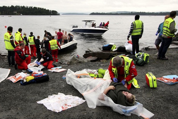 A wounded woman is brought ashore opposite Utoya island [in the distance] after being rescued from a gunman who went on a killing rampage targeting participants in a Norwegian Labour Party youth organisation event on the island, some 40 kilometres south-west of Oslo. PHOTO: AFP