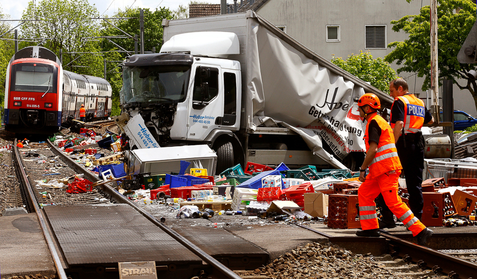 A rescue worker and a Swiss police officer stand beside a truck transporting beverages which crashed with a suburban train on a railroad crossing in Horgen, Switzerland. PHOTO: REUTERS