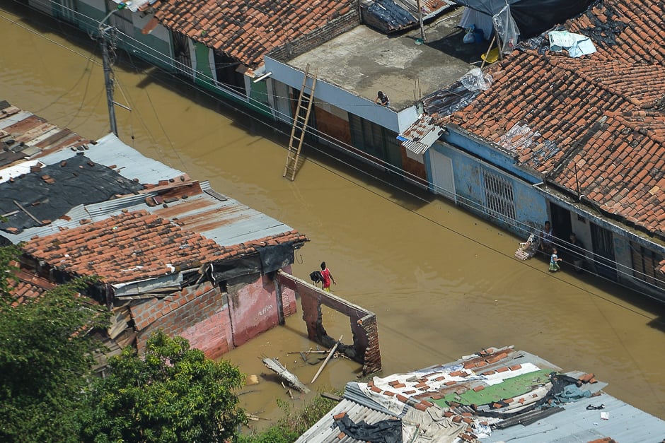 A woman walks along a flooded street in Cali, Colombia, after heavy rains caused the overflowing of the Cauca River. PHOTO: AFP