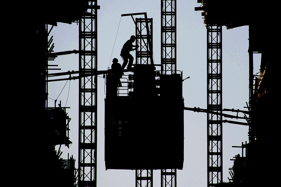 Workers stand on the roof of an elevator at the construction site of a new financial district in Beijing, China. PHOTO: REUTERS