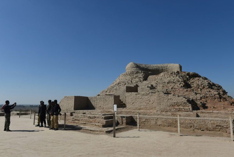 In this photograph taken on February 9, 2017, Pakistani policemen take a photograph alongside a Buddhist stupa at the UNESCO World Heritage archeological site of Mohenjo Daro some 425 kms north of Karachi. PHOTO: AFP