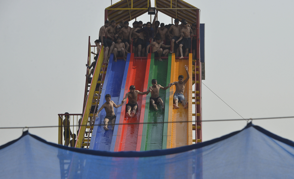 Pakistani youths play on a slide at a water park amid rising temperatures in Lahore. PHOTO: REUTERS