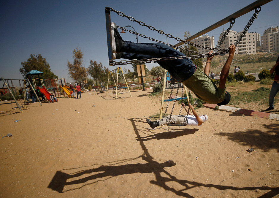 Palestinian protesters swing as they rest at a park during clashes with Israeli troops at a protest in support of Palestinian prisoners on hunger strike in Israeli jails, near the Jewish settlement of Beit El, near the West Bank city of Ramallah. PHOTO: REUTERS
