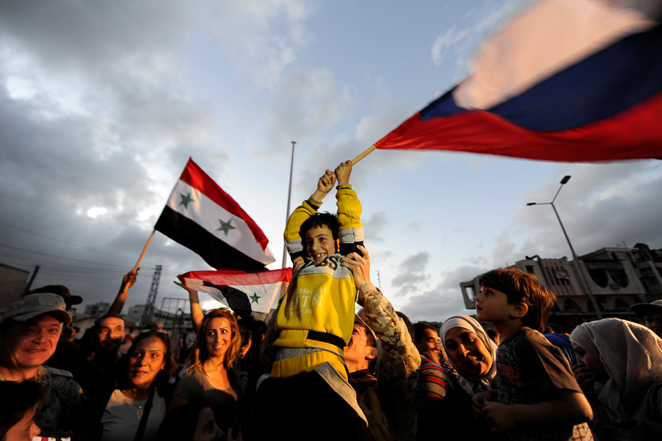 People celebrate carrying a Russian and Syrian national flags inside Waer district, after rebel fighters and their families evacuated the besieged Waer district in the central Syrian city of Homs, after an agreement was reached between rebels and Syria's army, Syria. PHOTO: REUTERS