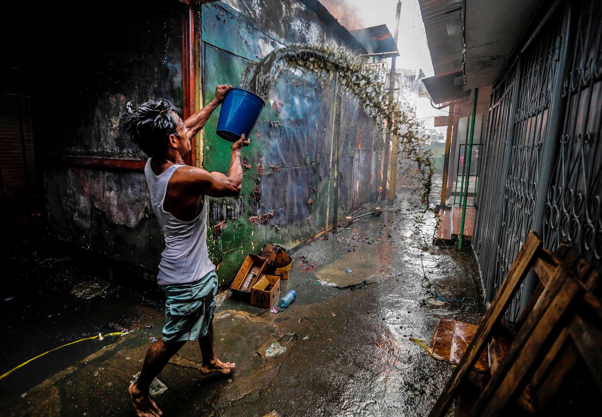 A man uses a bucket of water to help put out a fire in the Mercado Oriental, Managua, Nicaragua. PHOTO: AFP