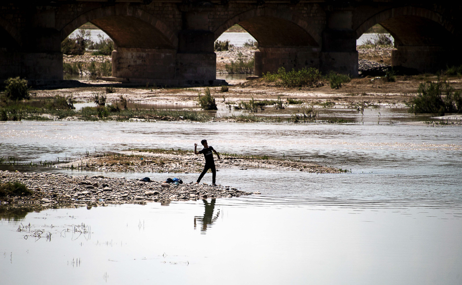 An Iraqi boy throws a stone into a river near Arbil, capital of the autonomous Kurdish region of northern Iraq. PHOTO: AFP