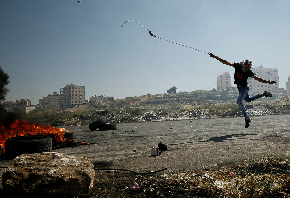 A Palestinian protester uses a sling to hurl stones towards Israeli troops during clashes at a protest in support of Palestinian prisoners on hunger strike in Israeli jails. PHOTO: REUTERS