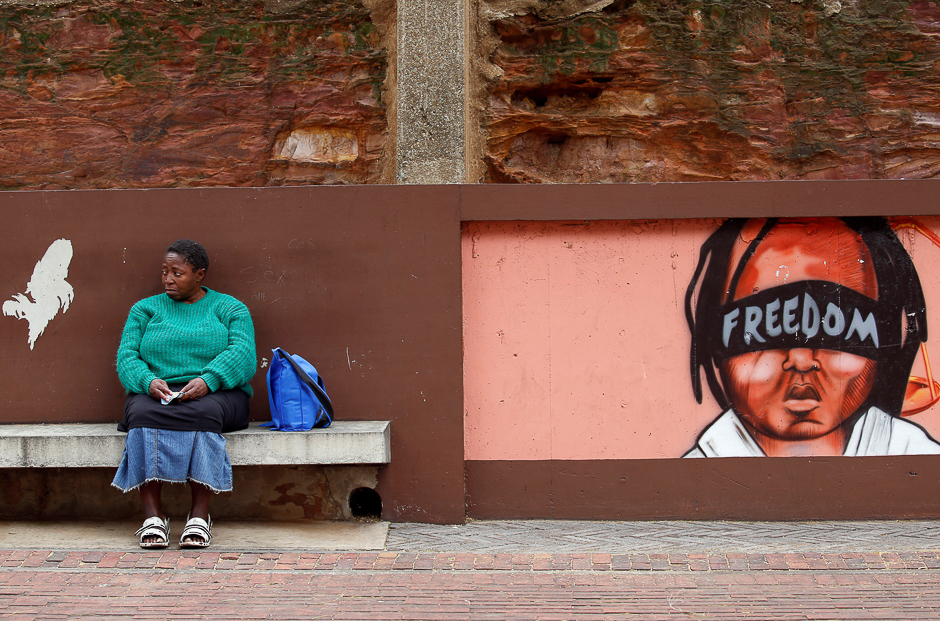 A woman sits next to murals as opposition parties march for the removal of President Jacob Zuma outside the Constitutional Court in Johannesburg, South Africa. PHOTO: REUTERS