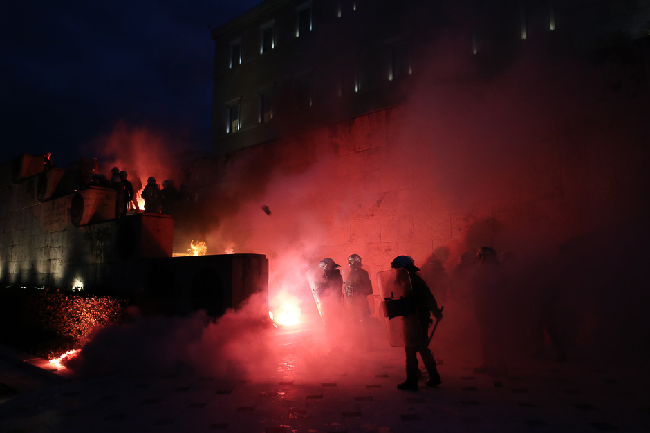 Riot police stand among flare smoke on the Tomb of the Unknown Soldier burns during clashes outside the parliament building as Greek lawmakers vote on the latest round of austerity Greece has agreed with its lenders, in Athens, Greece. PHOTO: REUTERS