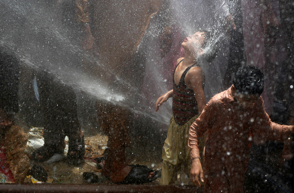 A boy cools off with others with water from water lines after they punctured them in protest against the power outages in their area, in Karachi. PHOTO: REUTERS