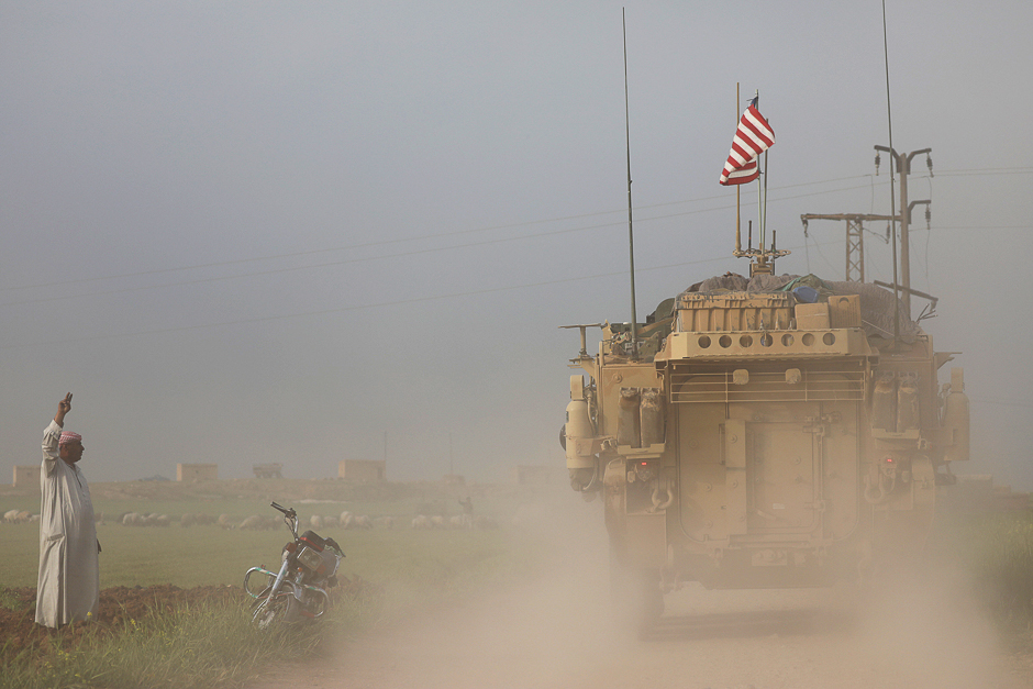 A man gestures at US military vehicles driving in the town of Darbasiya next to the Turkish border, Syria. PHOTO: REUTERS