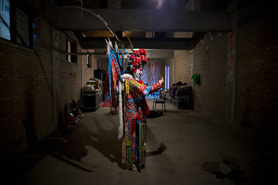 A Jin opera performer uses her mobile phone to take a selfie backstage at an outdoor theatre in Yu county, or Yuxian, in northern Hebei province. PHOTO: AFP