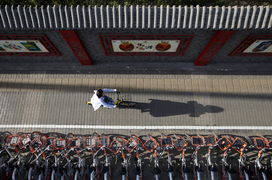 A woman rides an Ofo's shared bike past Mobike's shared bikes in Beijing's central business area, China. PHOTO: REUTERS