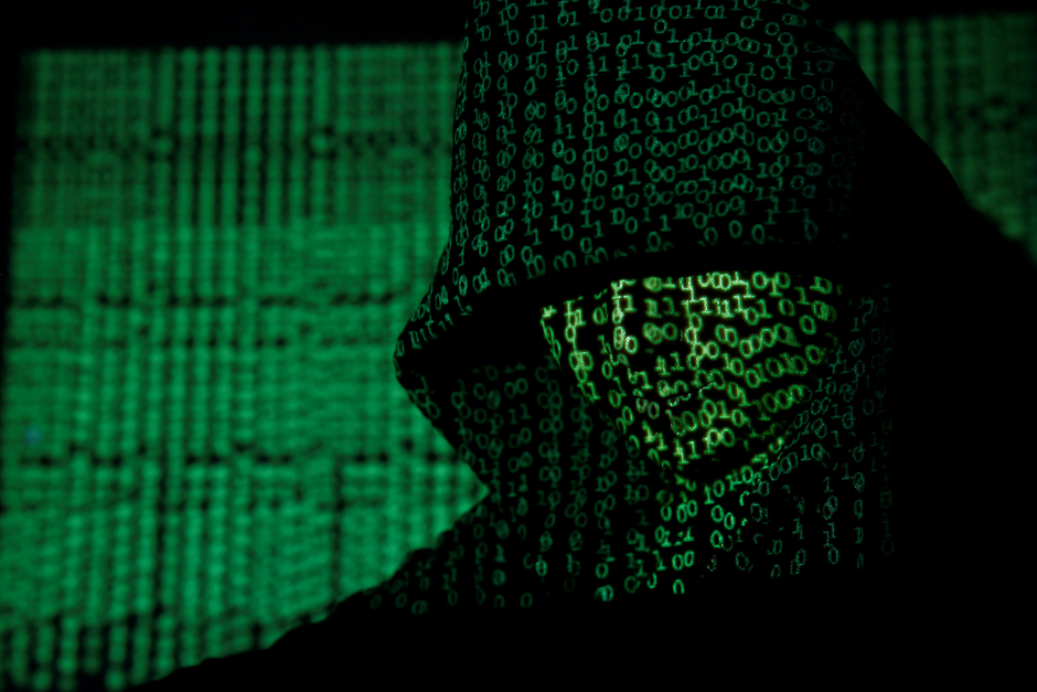 A projection of cyber code on a hooded man is pictured in this illustration picture. Capitalising on spying tools believed to have been developed by the US National Security Agency, hackers staged a cyber assault with a self-spreading malware that has infected tens of thousands of computers in nearly 100 countries. PHOTO: REUTERS